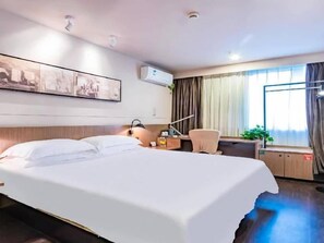 Une chambre d’hôtel avec un lit, un bureau, une chaise et une fenêtre avec des rideaux.
