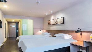 A hotel room with two beds, a bedside table, a wall-mounted lamp, and a ceiling-mounted smoke detector. - Jinjiang Inn Select (Hangzhou Binjiang University Town Puyan Metro Station) (Hangzhou)