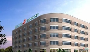 Un hotel de varios pisos con fachada curva, numerosas ventanas y un letrero llamativo en la parte superior.