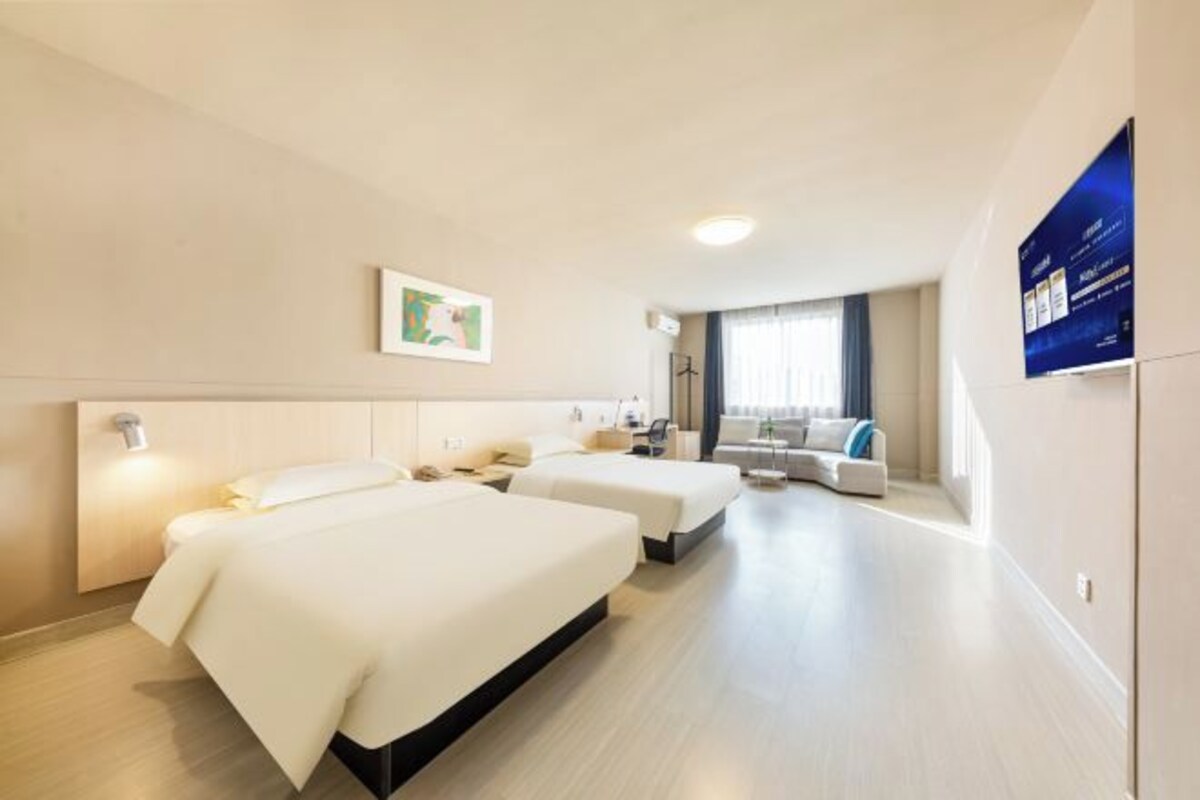 Una habitación de hotel con dos camas, un sofá y una televisión.