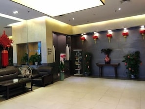 Un hall d’entrée moderne avec des sièges en cuir, un comptoir d’accueil et des lanternes rouges accrochées au mur.