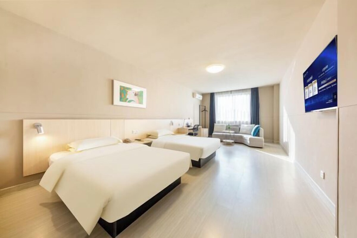 Une chambre d’hôtel avec deux lits, un canapé et une télévision.