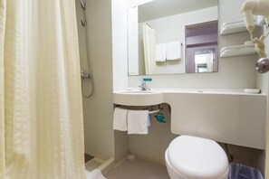 Un baño con ducha, lavabo, inodoro y espejo.