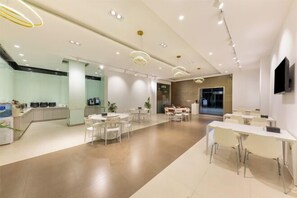 Un hall d'hôtel moderne avec un comptoir d'accueil, un espace salon et une cuisine en arrière-plan.