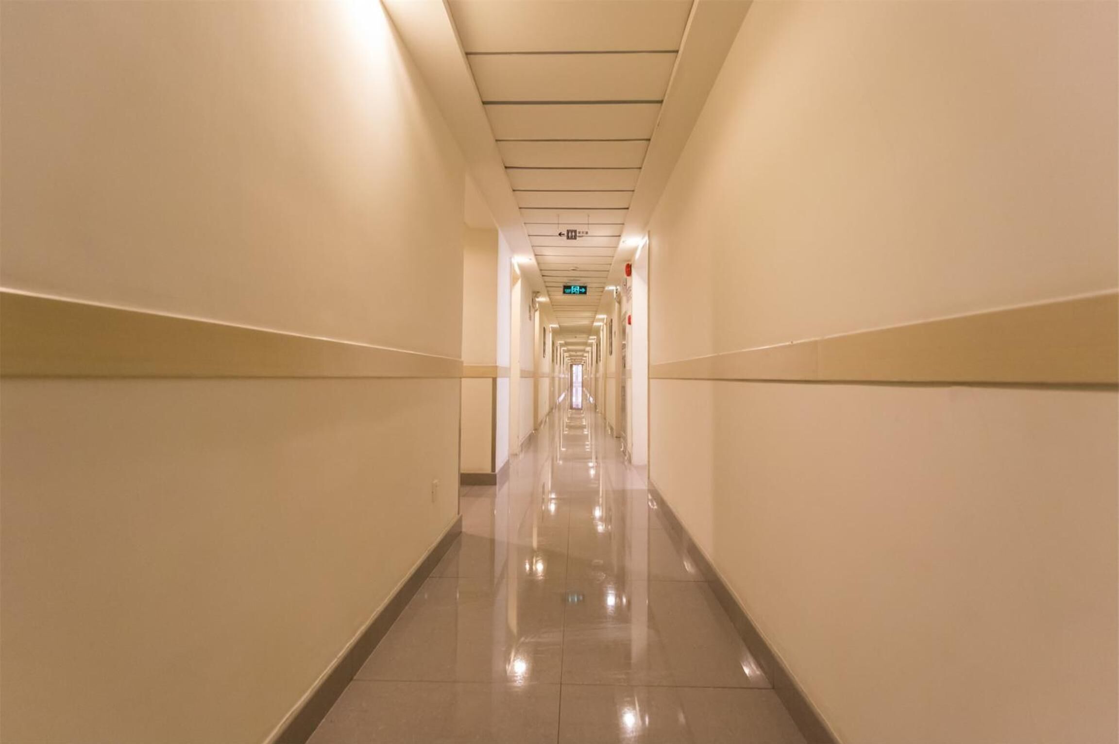 A long, narrow hallway with a shiny floor and white walls.