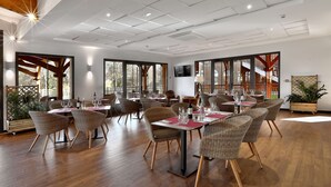 A spacious dining area with wooden flooring, wicker chairs, and tables set for dining.