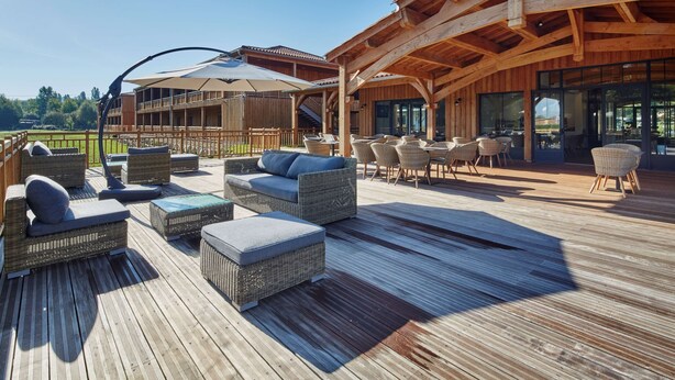 A wooden deck with wicker furniture and a covered seating area.
