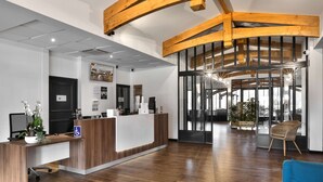 A reception area with a wooden reception desk, a blue sofa, and a large window with a view of the outdoors.
