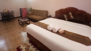 Une chambre d’hôtel avec un grand lit, un canapé, une table à manger et une petite table avec une chaise.