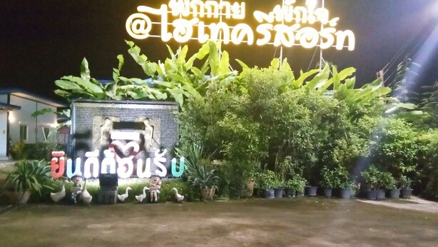 Une entrée bien éclairée, avec une grande enseigne lumineuse, des plantes en pot et une petite statue représentant une figure.