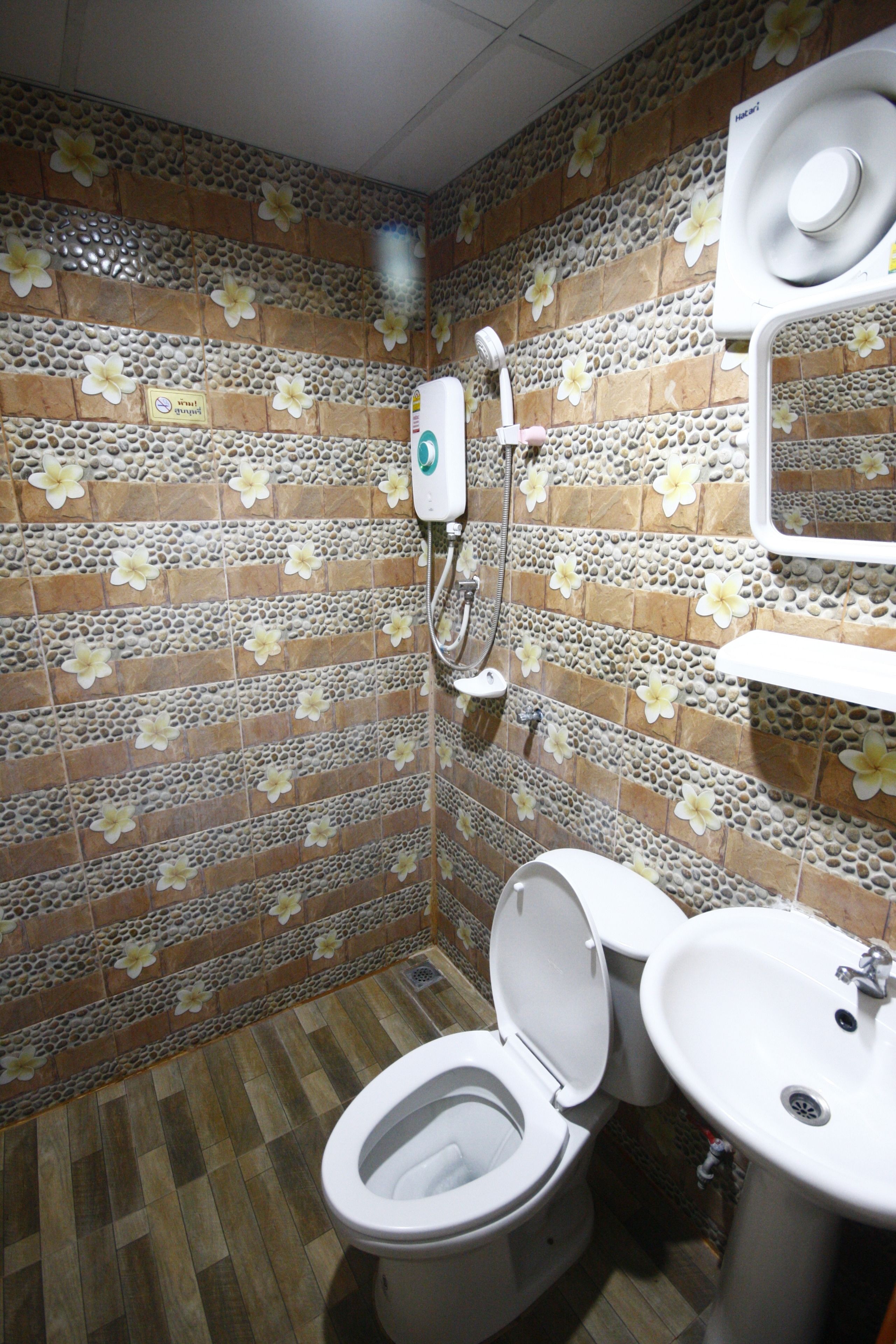 A bathroom with a toilet, sink, and shower. The walls are tiled with a floral pattern.