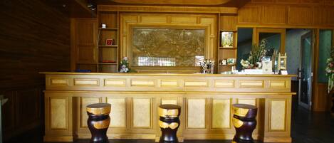 A wooden bar area with a large window, wooden cabinets, and three wooden stools.