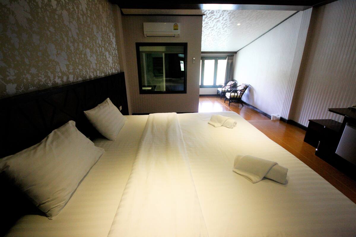 A hotel room with a large bed, a headboard, a window, and a view of the outside.