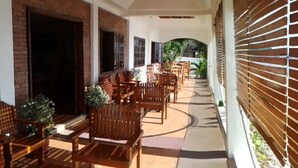 An outdoor patio with wooden furniture and a brick wall. - Sogod Bay Scuba Resort (Padre Burgos)