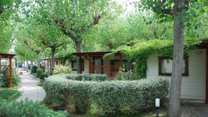 A garden pathway leading to a row of cottages with wooden fences and greenery. - Centro Vacanze Camping Spinnaker (Fermo)