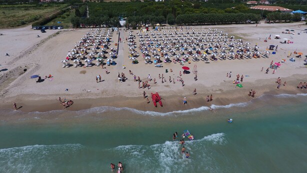 An aerial view of a beach with numerous umbrellas and sun loungers, indicating a large beach area. - Centro Vacanze Camping Spinnaker (Fermo)