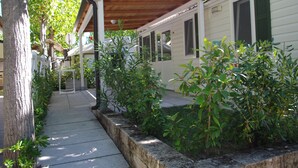 A row of mobile homes with a covered walkway and greenery. - Centro Vacanze Camping Spinnaker (Fermo)