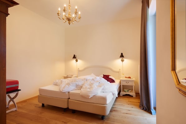 A bedroom with a double bed, bedside tables, a nightstand, a chandelier, and a mirror.