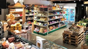 A grocery store with shelves stocked with various products, a refrigerated section, and a display of bread and pastries.