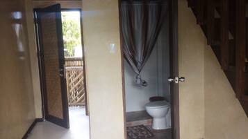 An open door leading to a bathroom with a toilet and a shower curtain.