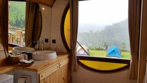 A bathroom with a large mirror, two sinks, and a view of tents and greenery outside. - Kiripura Resort (Khao Kho)