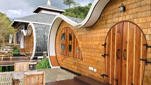 A building with a curved wooden exterior, large arched doors, and a small pagoda-like structure on the roof. - Kiripura Resort (Khao Kho)