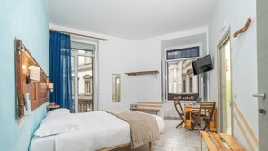 A hotel room with a bed, a desk, a chair, a TV, and a window with a view of buildings. - B&B DolceVita Napoli (Naples)