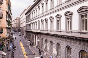 A historic street with buildings featuring classical architecture, a cobblestone street, and pedestrians. - B&B DolceVita Napoli (Naples)