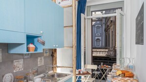 A kitchen with blue cabinets, a sink, and a dining area with a table and chairs. - B&B DolceVita Napoli (Naples)