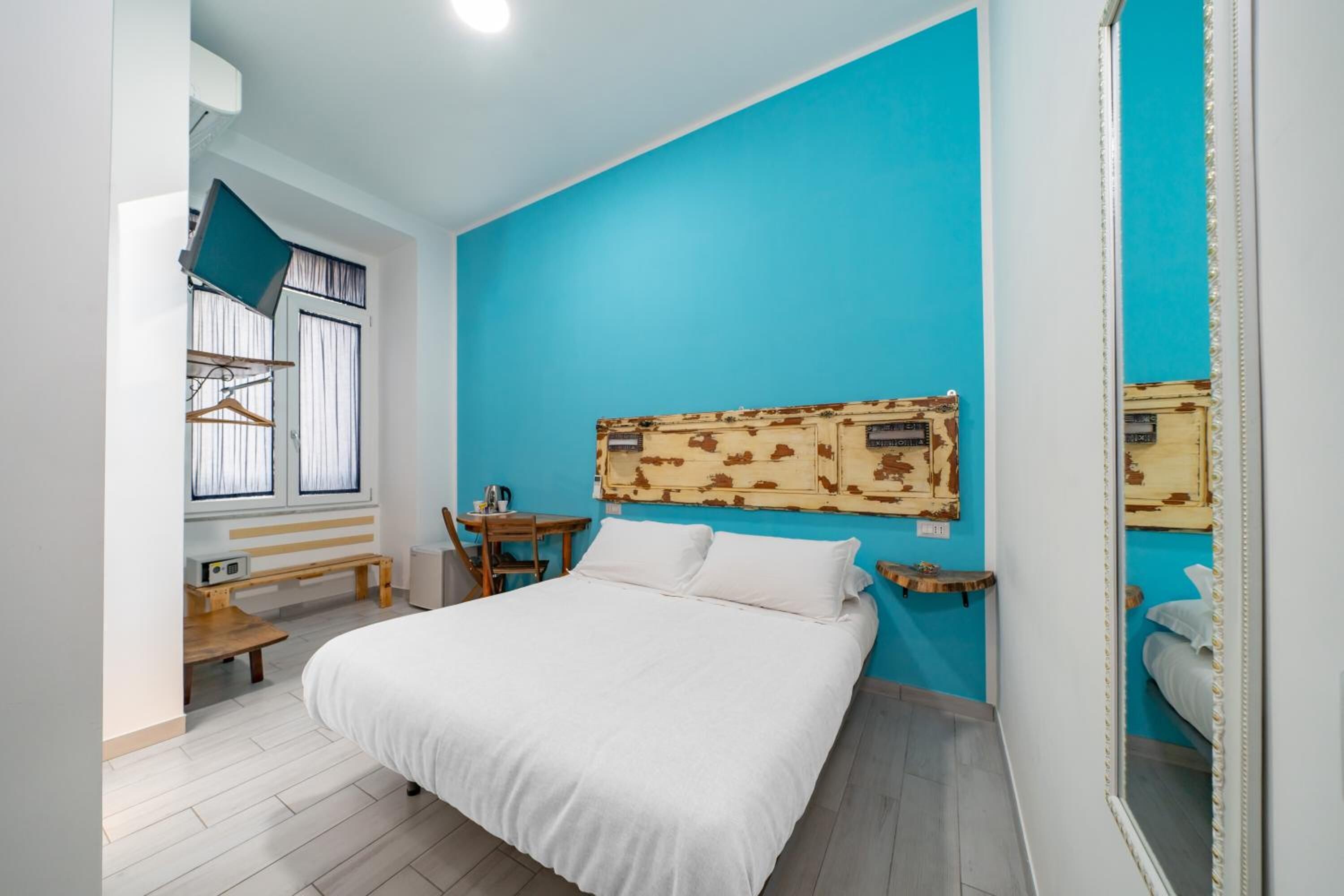A bedroom with a large bed, a wooden headboard, a small table, and a bench.