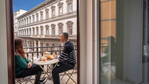 A balcony with a table and chairs, overlooking a building with classical architecture. - B&B DolceVita Napoli (Naples)