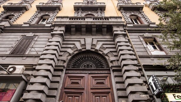 A building facade with a central arched entrance, multiple balconies, and a sign indicating a tabac store. - B&B DolceVita Napoli (Naples)