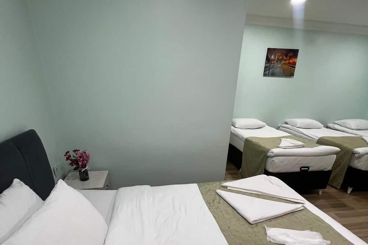 Habitación de hotel con una cama grande, una mesita de noche con un florero y una camilla de masaje con toallas.