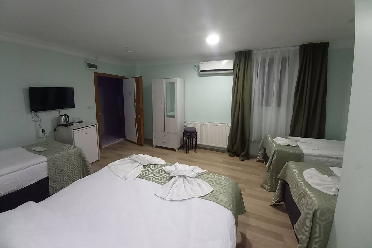 Habitación de hotel con dos camas, televisión, armario, escritorio y ventana con cortinas.