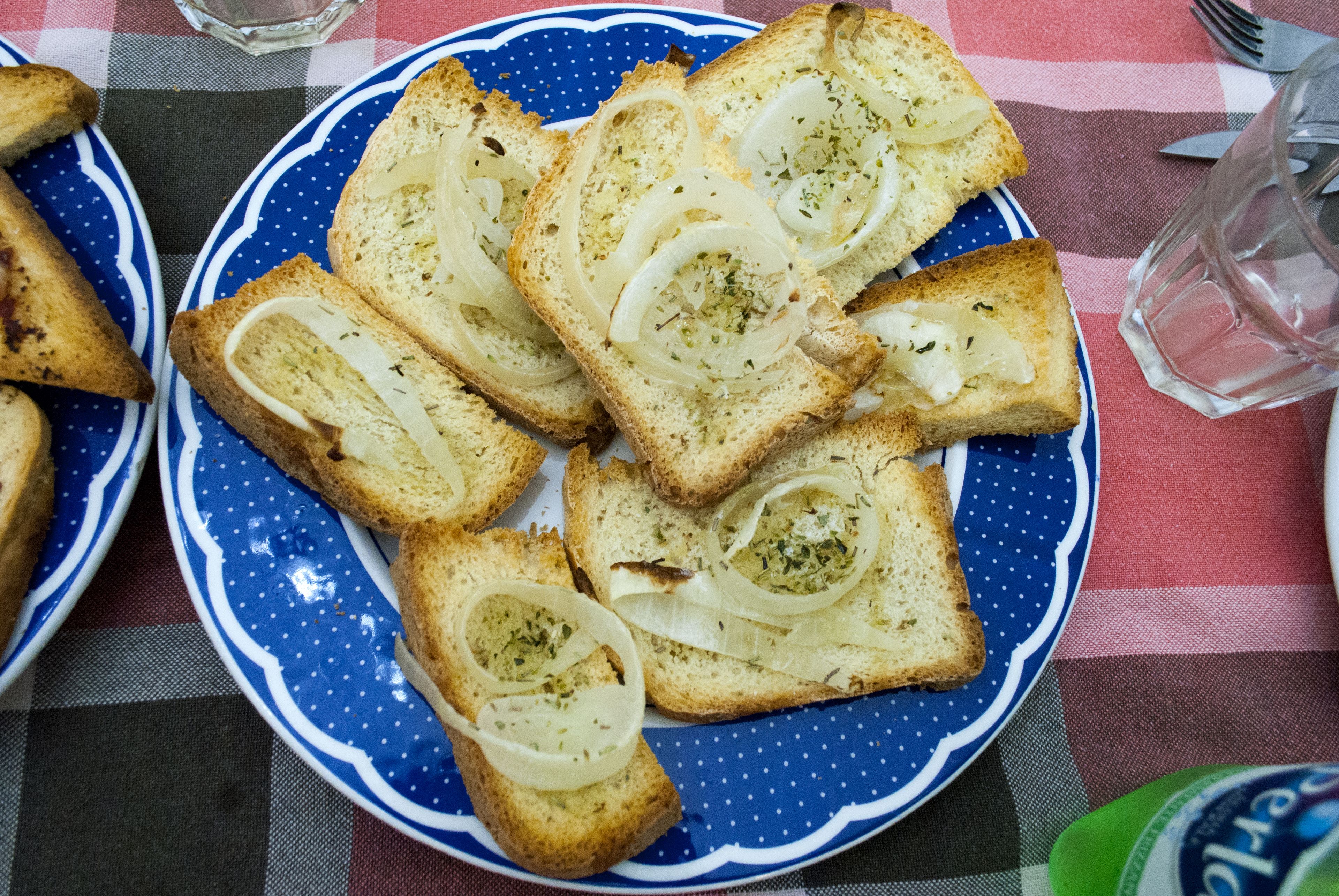 Een bord knoflookbrood op een blauw-wit geruit tafelkleed.