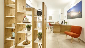 Un intérieur moderne avec des étagères en bois, un fauteuil rouge et un bureau avec un ordinateur.