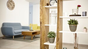 Un salon moderne avec un canapé bleu, une table basse en bois et une étagère blanche agrémentée d’objets décoratifs.