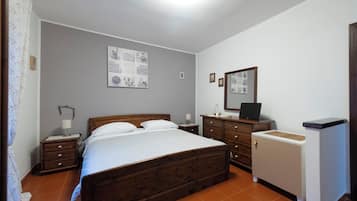 A bedroom with a wooden bed, a nightstand, a dresser, and a mirror.