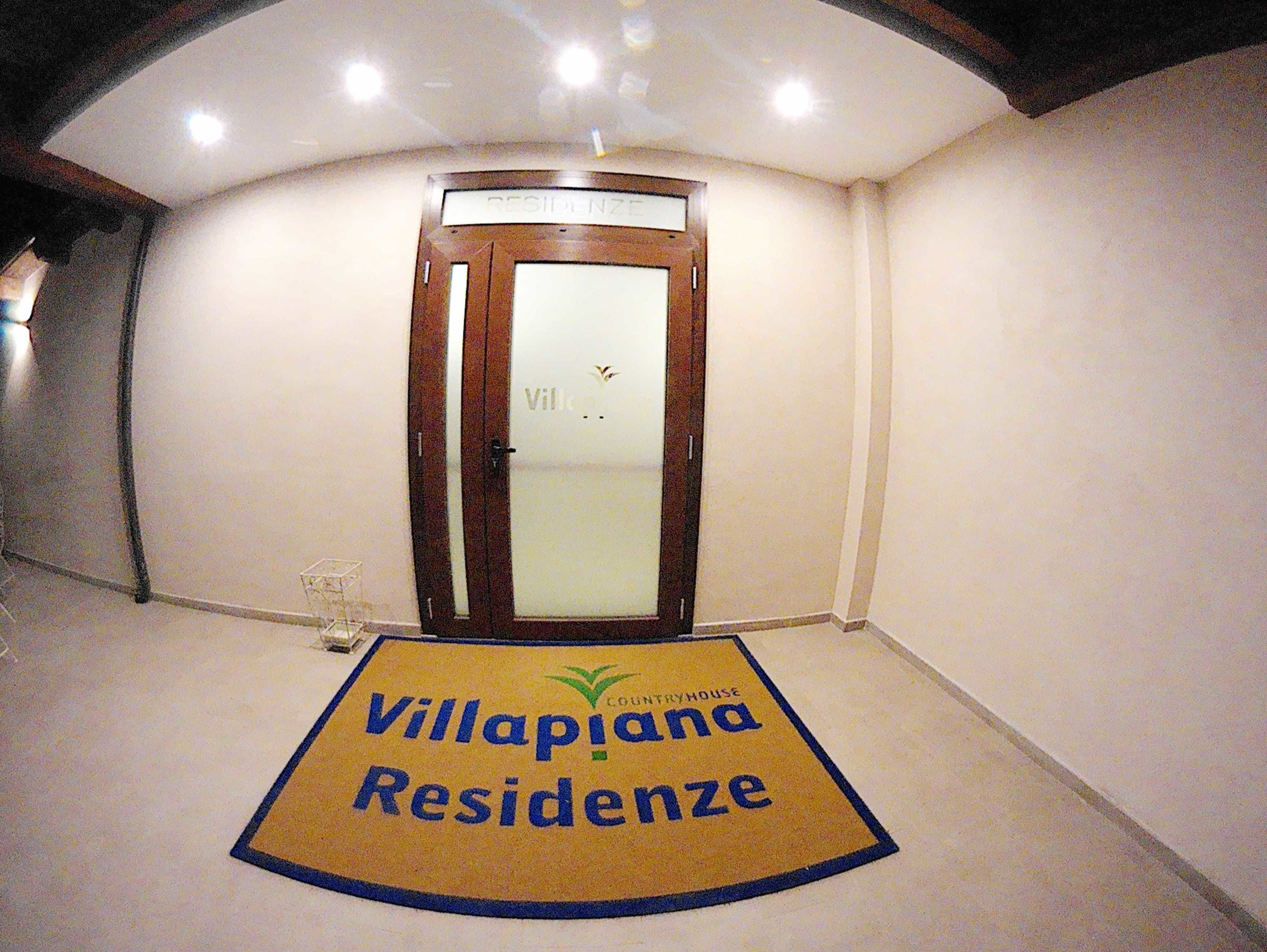 L’entrée d’un hôtel, avec une porte tournante, un comptoir d’accueil et un paillasson portant le nom de l’hôtel.