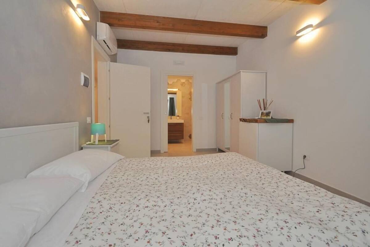 Ein Schlafzimmer mit einem Bett, einem Nachttisch, einer Lampe und einem Holzbalken an der Decke.