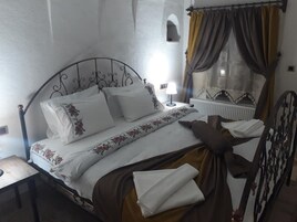 A neatly made bed with floral bedding, a bedside lamp, and a window with curtains.