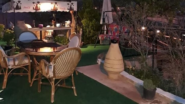 Un patio exterior con mesa y sillas, una pequeña barra y un paraguas decorativo.