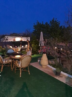 Zona de terrassa a l'exterior amb taula i cadires, un petit bar i un parasol decoratiu.