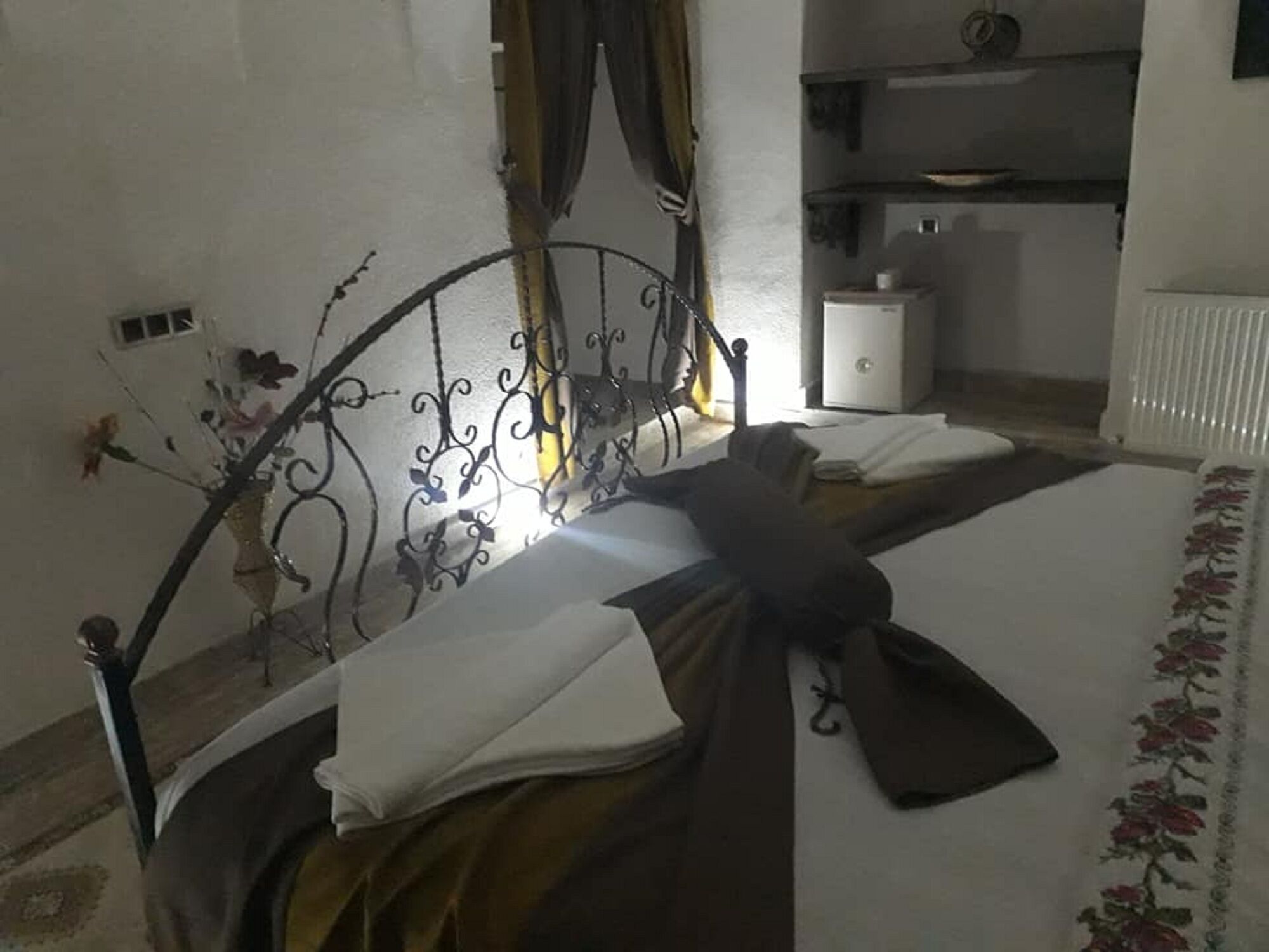 A bed with a metal headboard, a white bedside table, and a radiator.