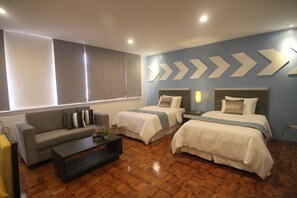 A hotel room with two beds, a sofa, a coffee table, and a large window with curtains. - Bryan Condo Makati (Makati)