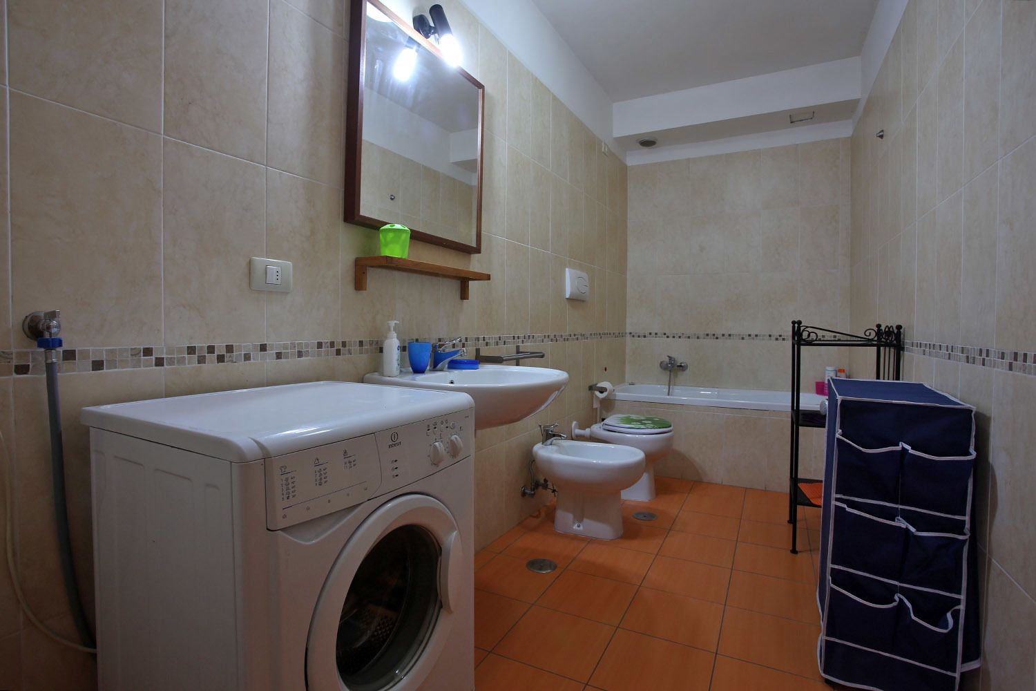 Een badkamer met een wasmachine, wastafel, toilet en bad.
