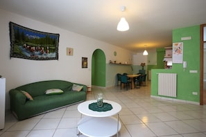 A living room with a green sofa, a white coffee table, and a dining area with a table and chairs. - La Cascata Palazzo Pellegrino (Vietri sul Mare)