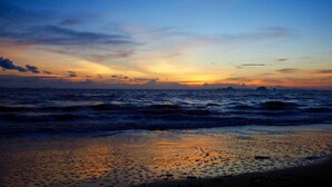 Una spiaggia al tramonto, con onde e cielo sereno.