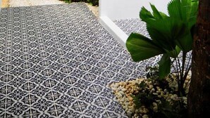 Un bagno moderno con un pavimento a motivi geometrici, un soffitto con luci lineari e piante tropicali.