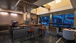 Uma área de bar moderna com balcão, banquetas e uma grande janela com vista para um horizonte urbano.